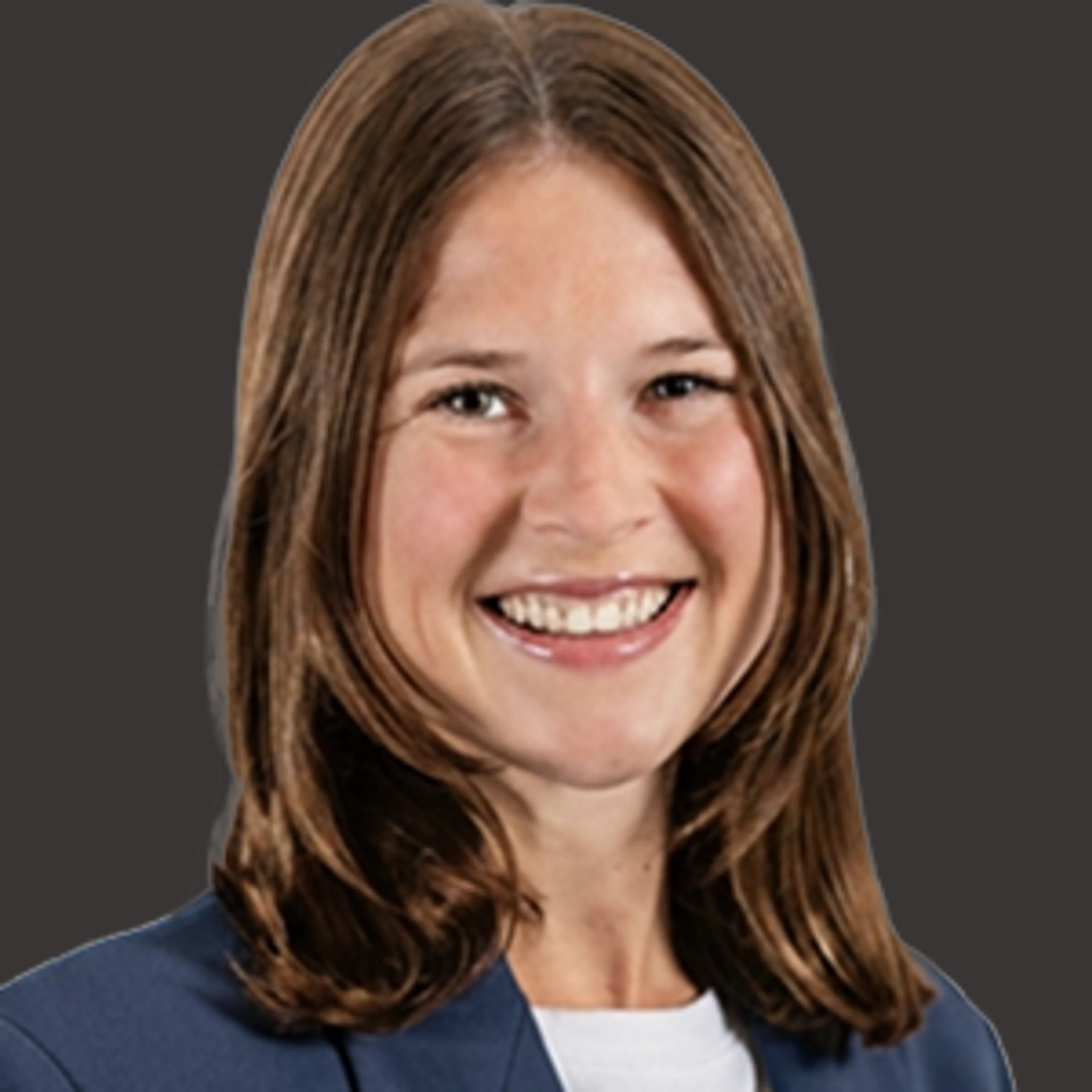 Smiling young woman with straight, shoulder-length brown hair, wearing a dark blazer and white top, posed in front of a plain dark background.