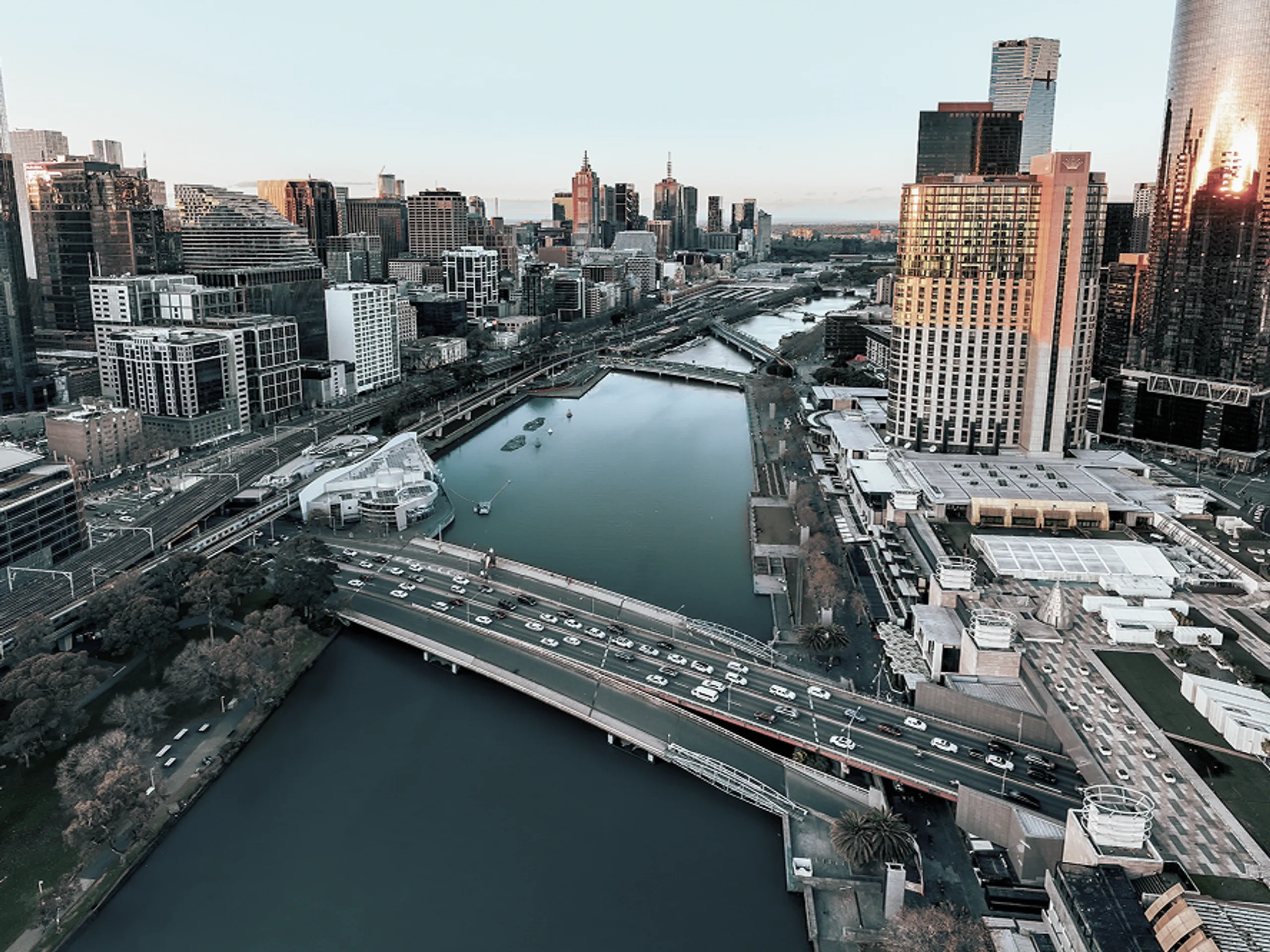 Aerial view of a city with a river running through the center, several bridges, tall buildings, and traffic on the roads during daylight.