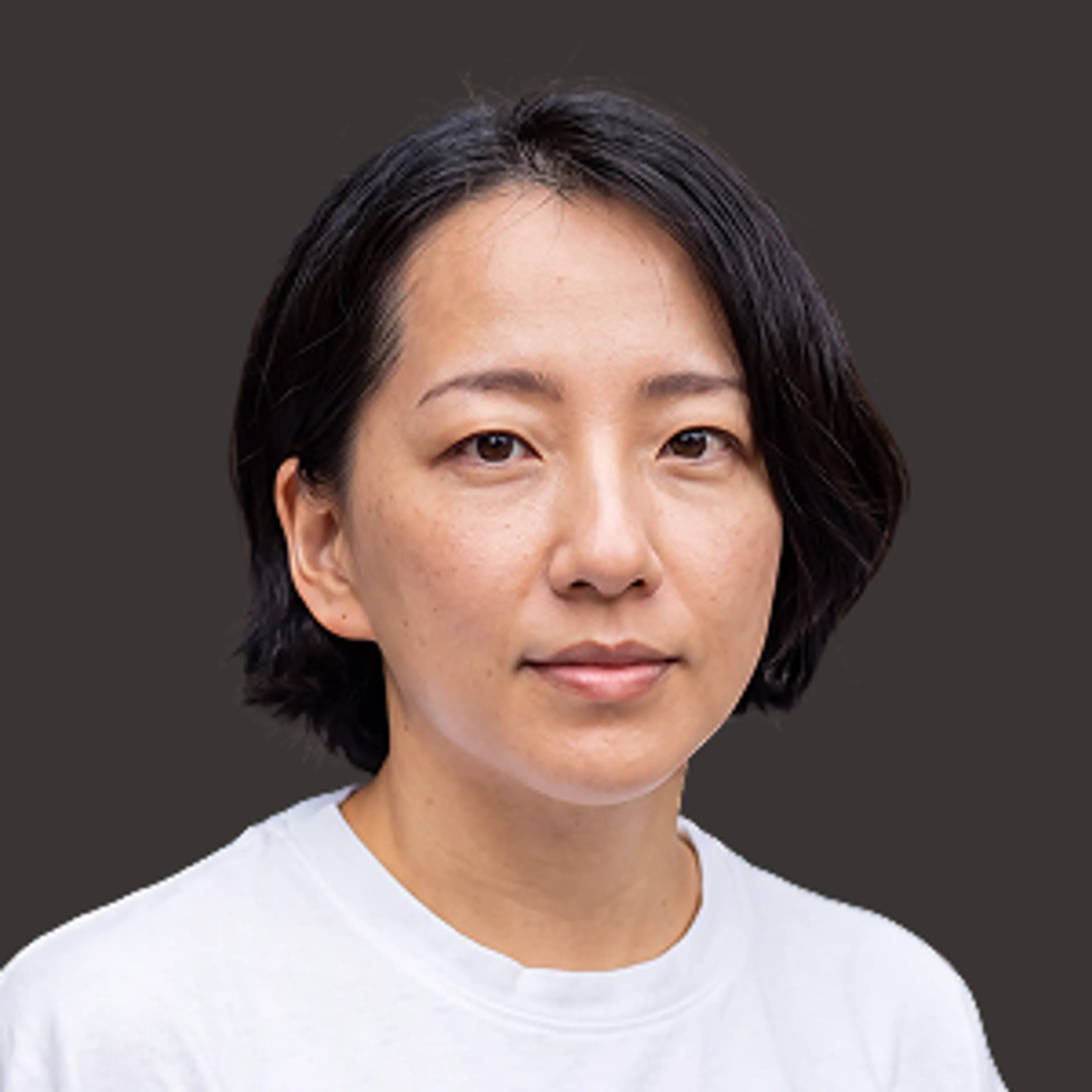 A person with dark hair wearing a white shirt, looking directly at the camera.