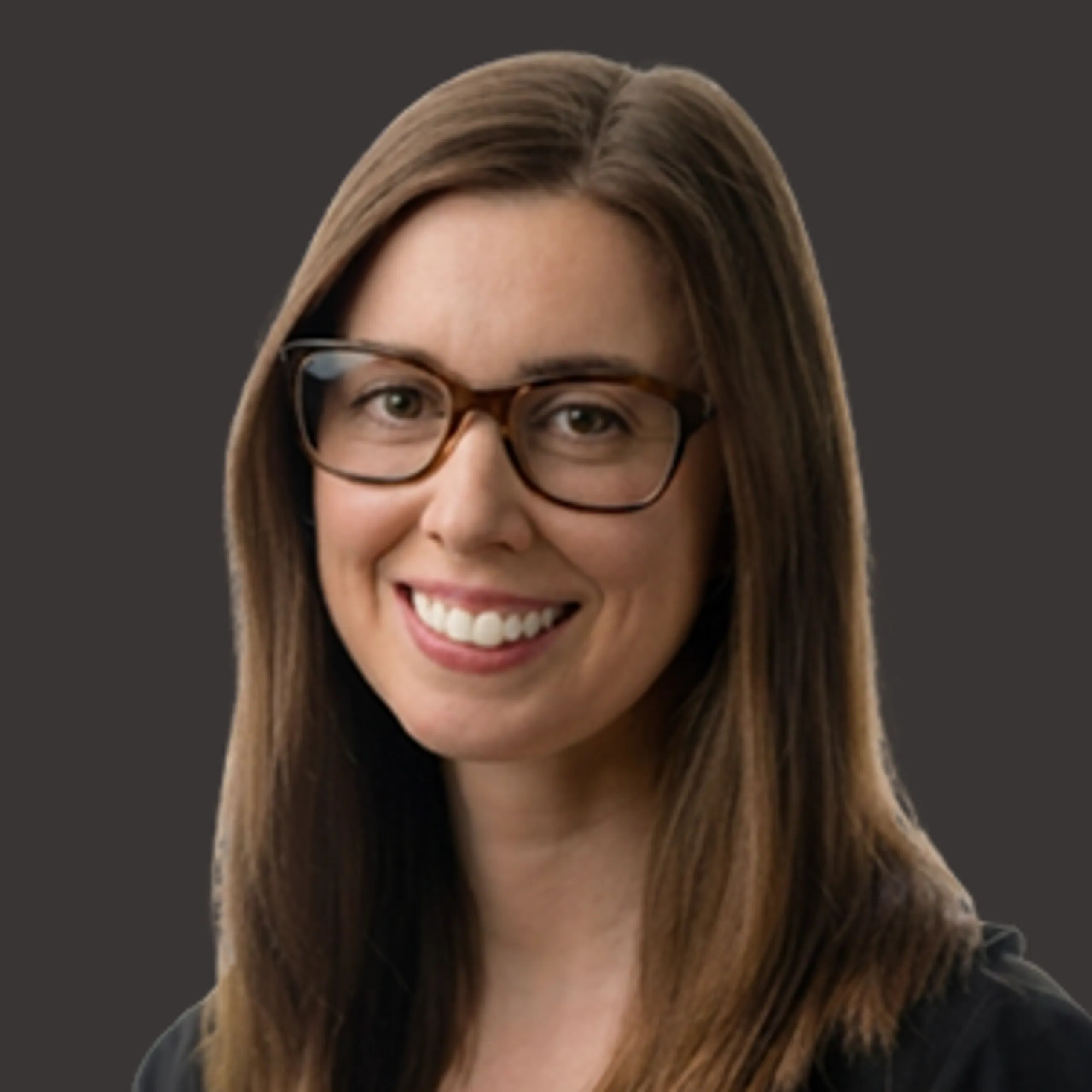 Woman with long straight brown hair and glasses, smiling, wearing a black top, in front of a plain dark gray background.