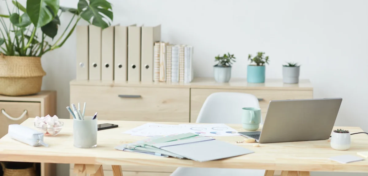 A desk featuring a laptop, a cup of coffee, and a small green plant, creating a cozy workspace atmosphere.