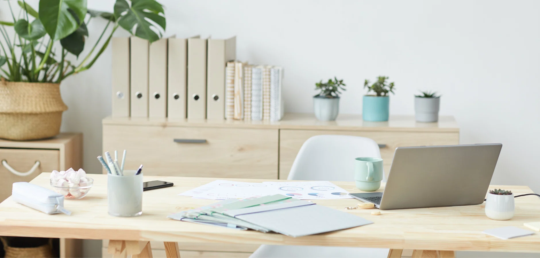 A desk featuring a laptop, a cup of coffee, and a small green plant, creating a cozy workspace atmosphere.