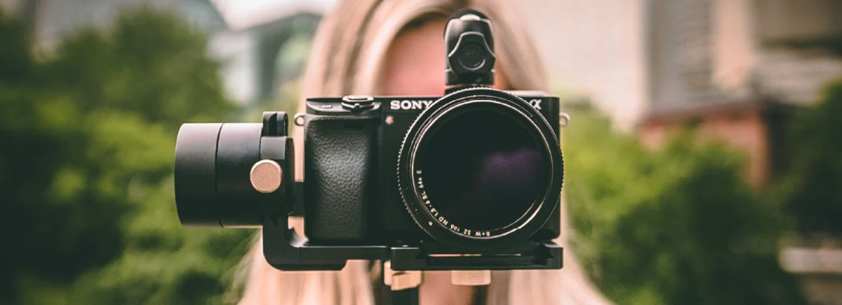 A woman holds a camera in front of her face, capturing a moment with a focused expression.