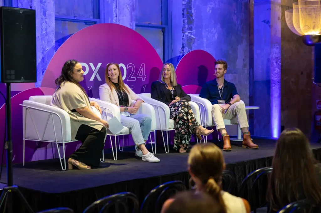 Four individuals seated on chairs against a vibrant purple backdrop, featuring Ashley Molyneux among them.