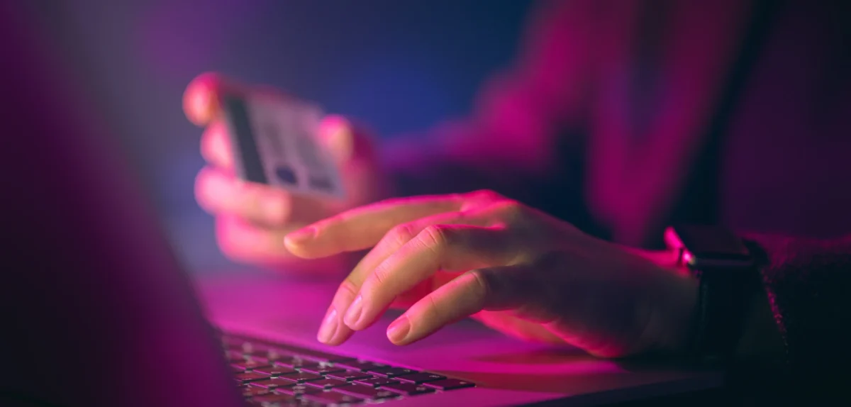 closeup of a woman's hand typing in her card details to shop online