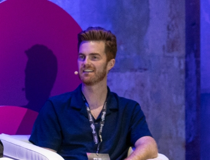 James Smith, sitting on chairs against a striking purple wall.