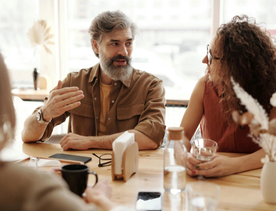 A man and woman engaged in conversation while seated at a table, sharing ideas and enjoying each other's company.