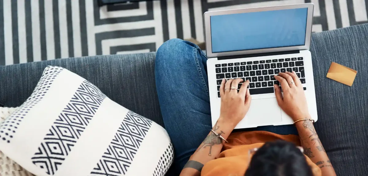 A woman seated on a couch, focused on her laptop, creating a cozy and productive home environment.