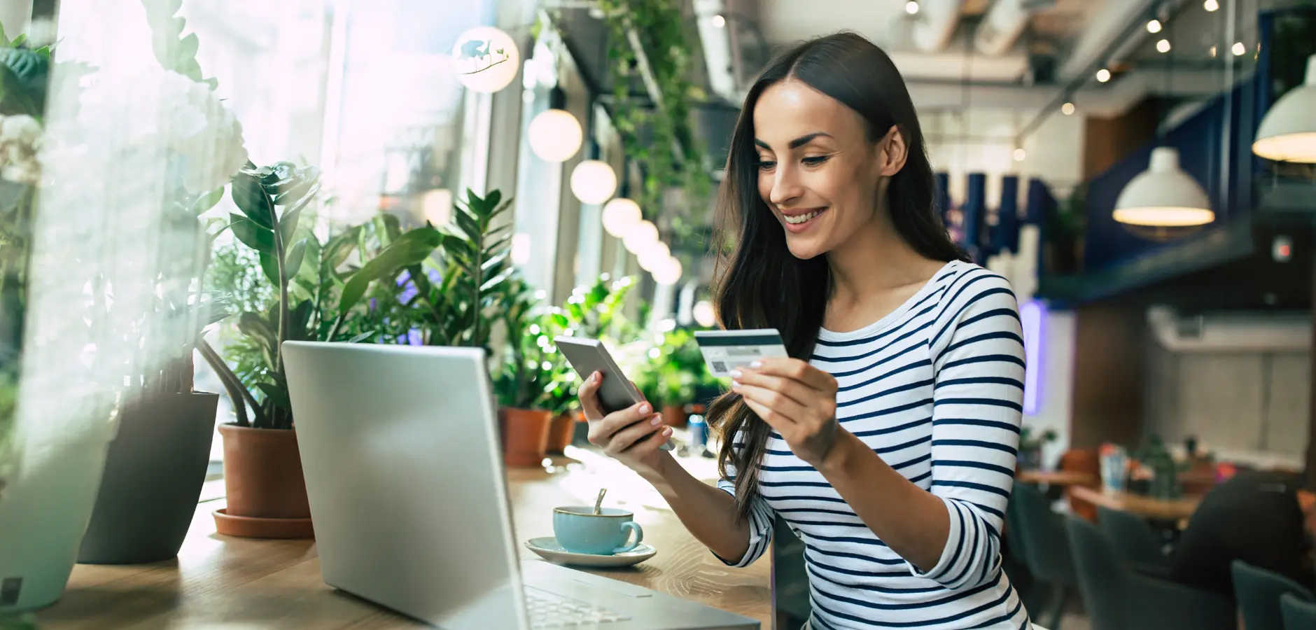 A person using a laptop while holding a credit card, engaged in an online transaction or shopping activity.