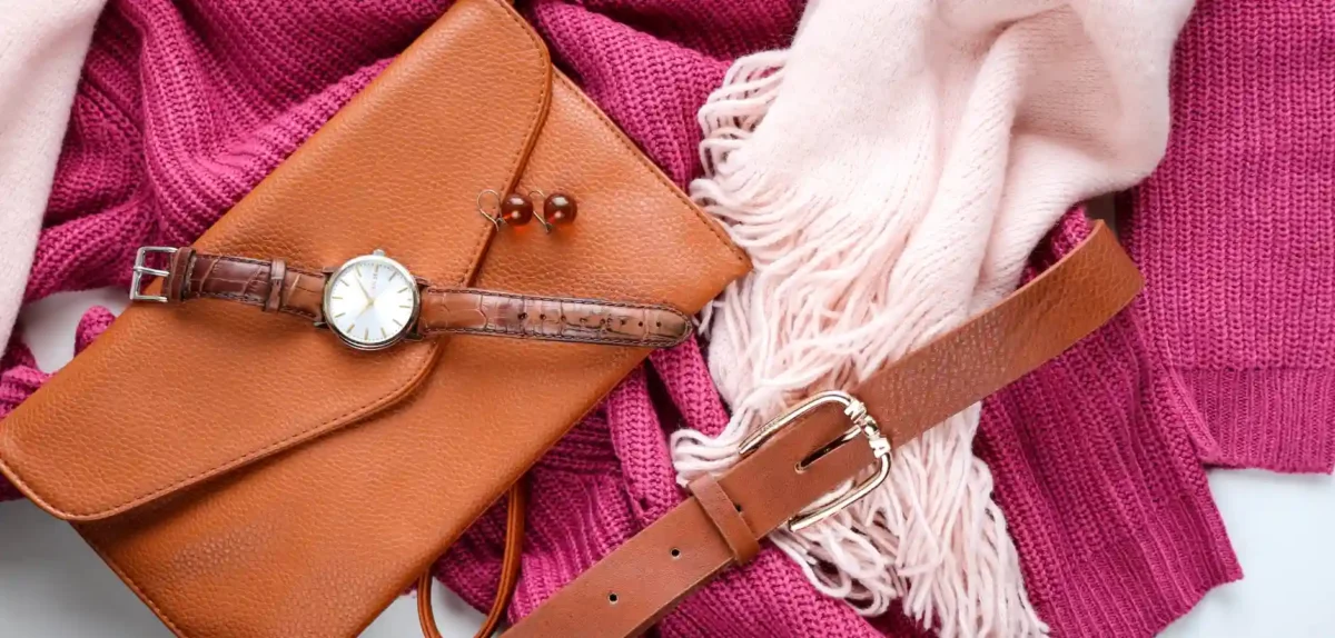 A pink sweater and scarf paired with a stylish brown purse, showcasing a chic and coordinated outfit.