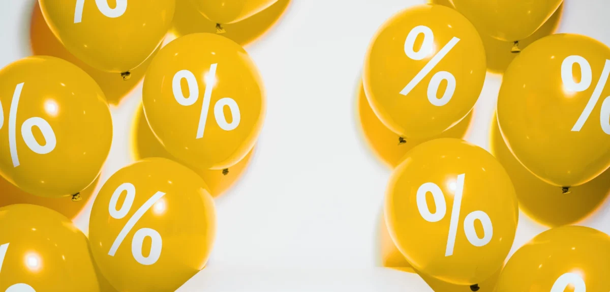 A cluster of yellow balloons featuring white percent signs, symbolizing discounts or promotions in a festive setting.