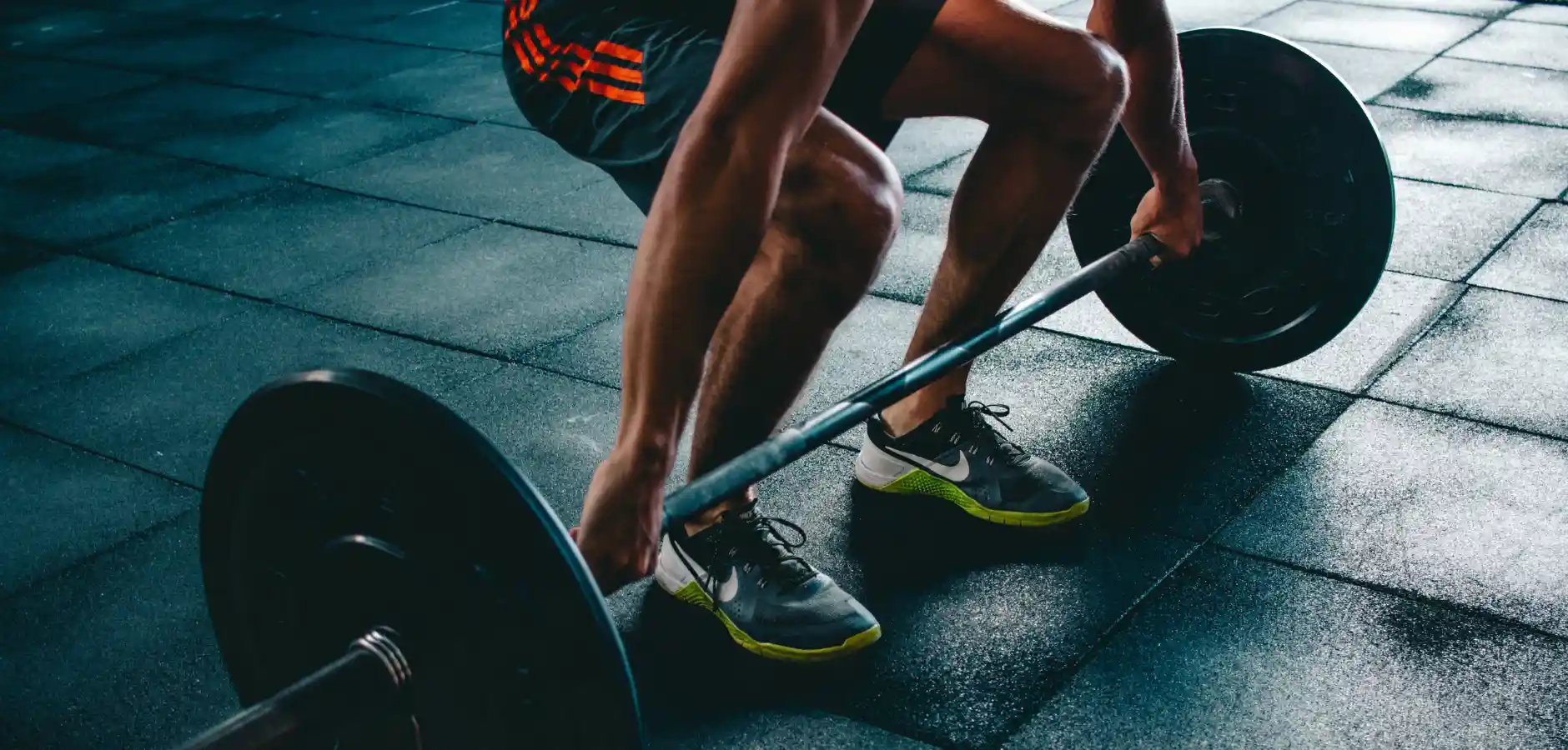 A person squats with a barbell, demonstrating strength and proper form in a gym setting.