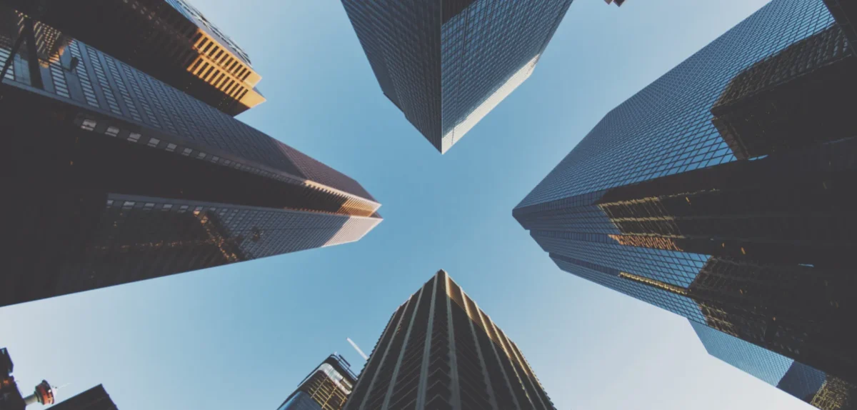 A view looking up at tall city buildings, showcasing a modern urban landscape with a focus on architectural heights.