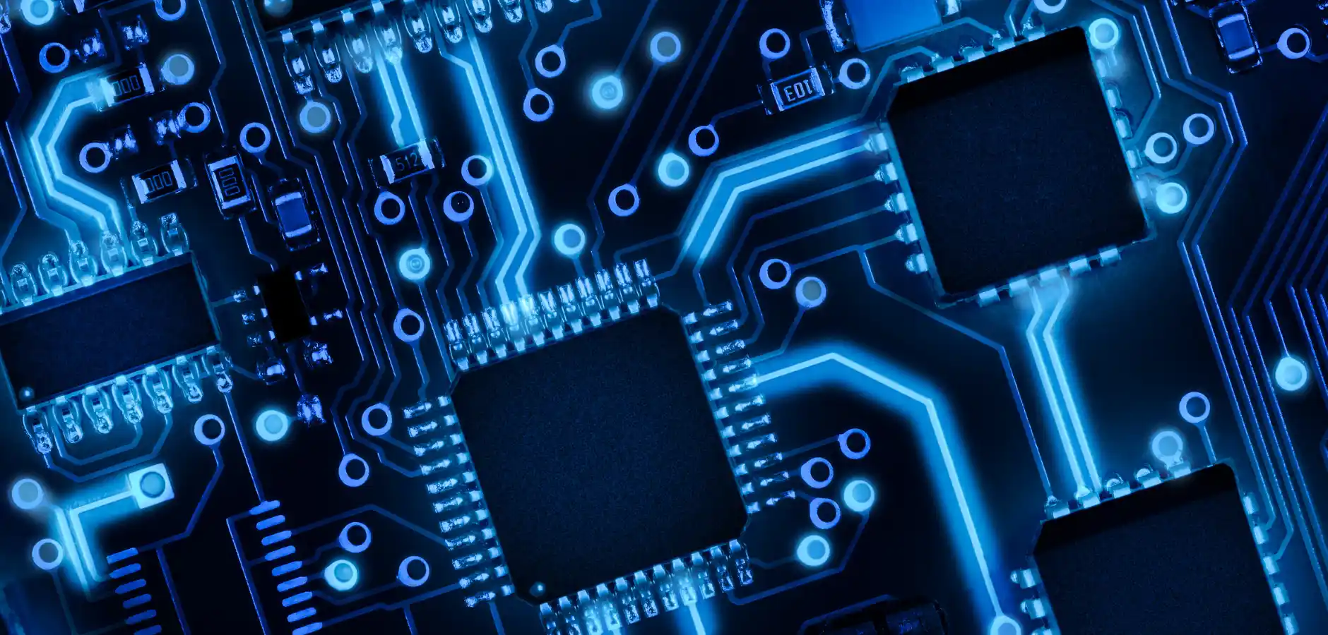 A close-up view of a circuit board illuminated by blue lights, showcasing intricate electronic components and connections.