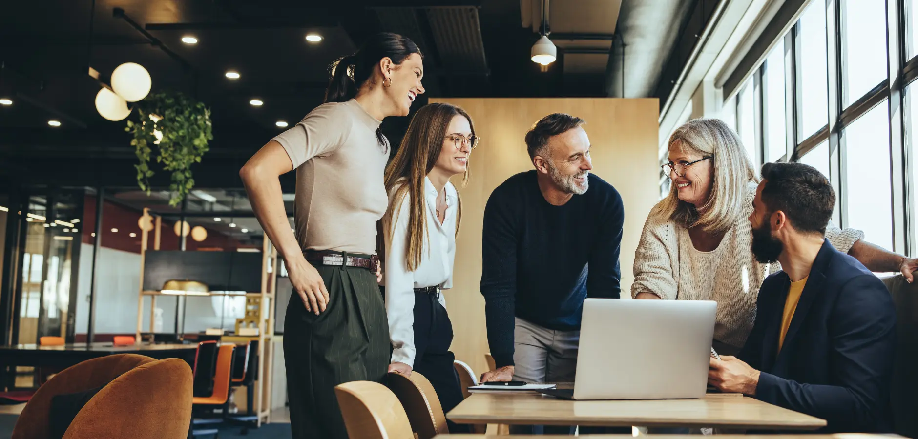 A team of people smiling around a laptop