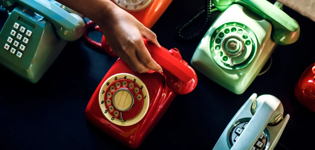 A person holds a phone in front of a display of various colorful phones.