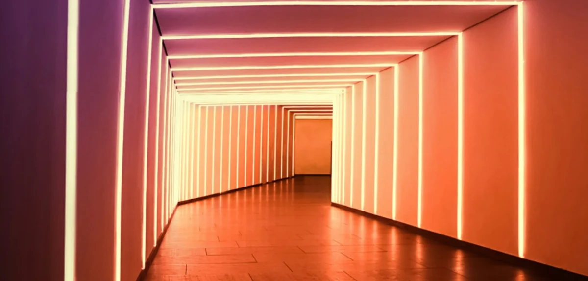 A long hallway with parallel illuminated lines on walls creating a perspective effect.