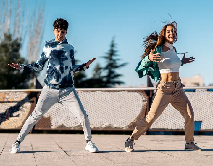 Two people dancing outdoors on a sunny day.