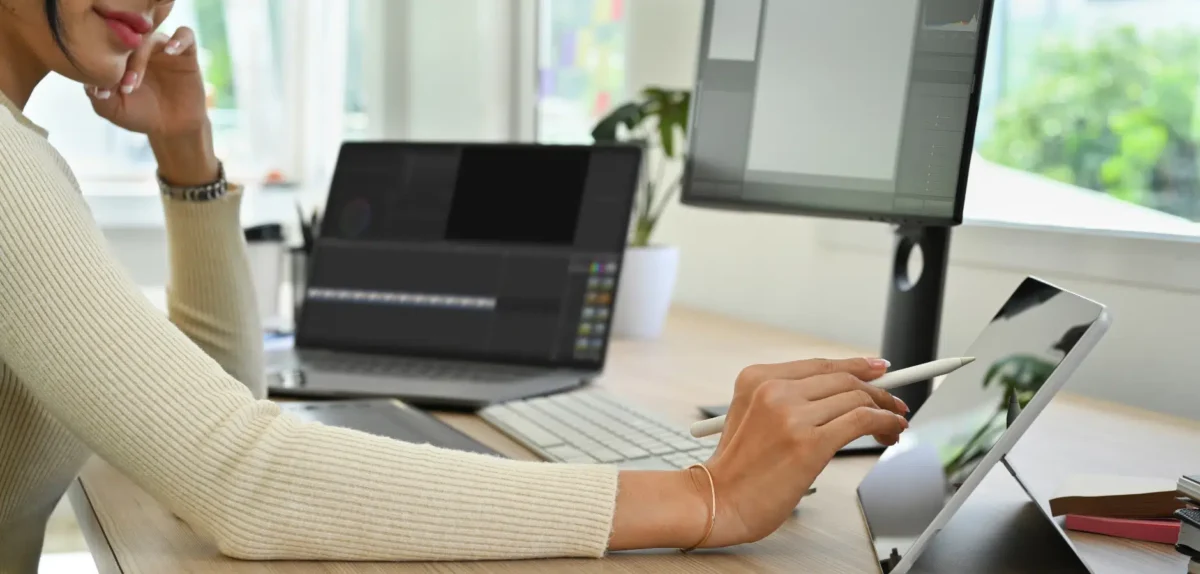 A woman sits at a desk, focused on her laptop while working.