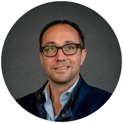 A smiling man in a suit and glasses, exuding confidence and professionalism.