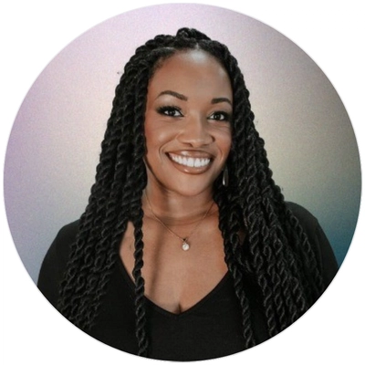 A smiling Black woman with long braids, radiating joy and confidence in a bright, inviting setting.