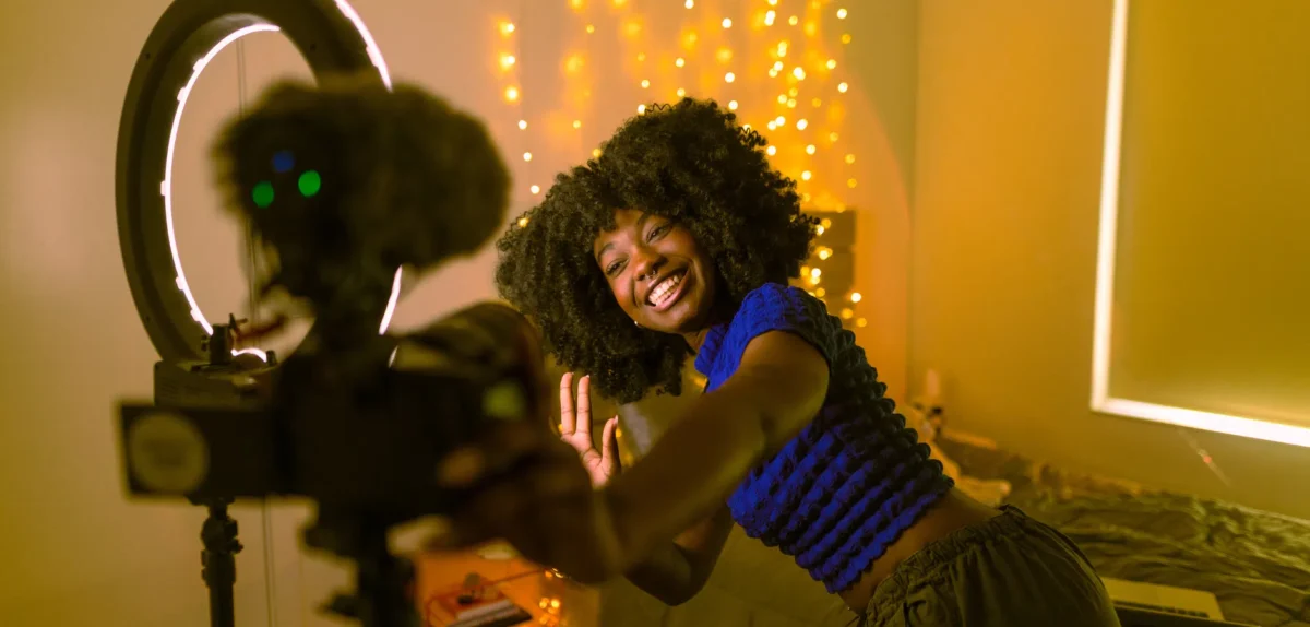 A woman smiles while taking a selfie with a camera, capturing a moment of joy and self-expression.