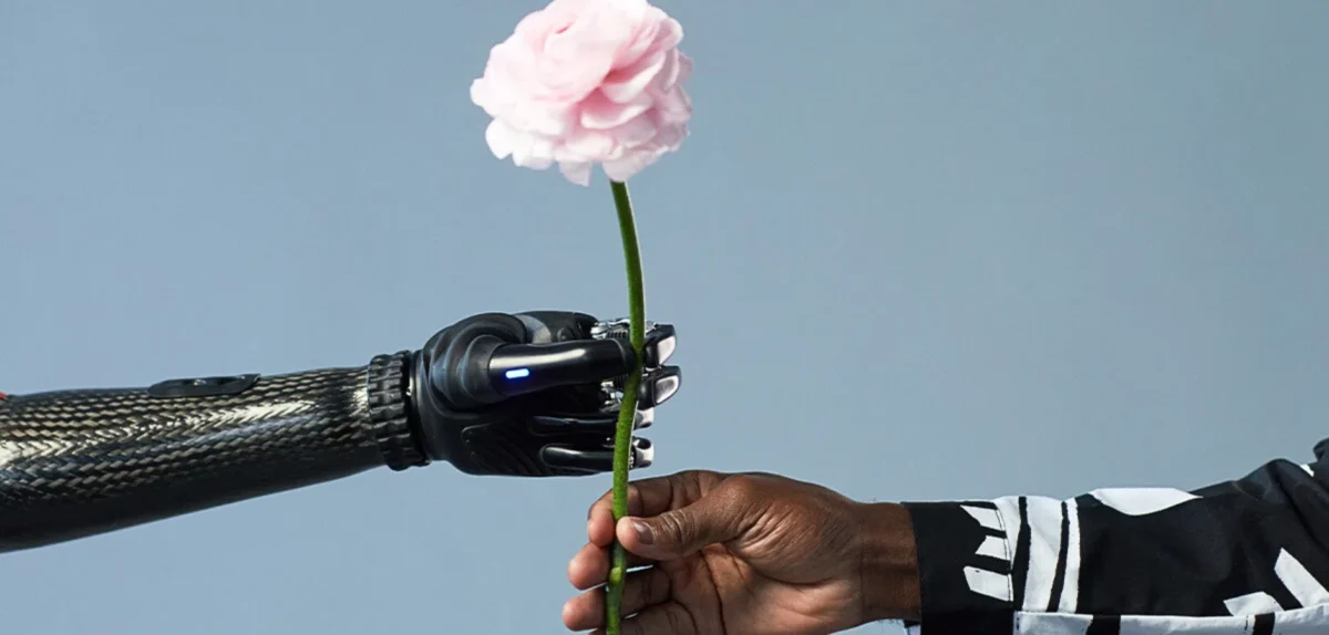 A man presents a flower to a robot, symbolizing a blend of nature and technology in a unique interaction.