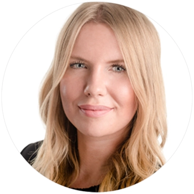 A woman with long, wavy blonde hair is smiling, wearing a black top against a white background in a circular cropped image.