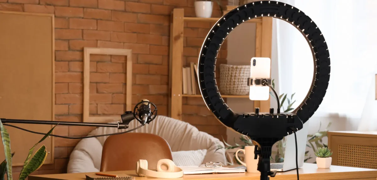 A ring light positioned on a desk, illuminating a laptop in front of it.