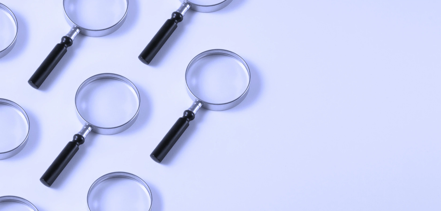 A collection of six magnifying glasses arranged on a white surface, showcasing their varying sizes and designs.