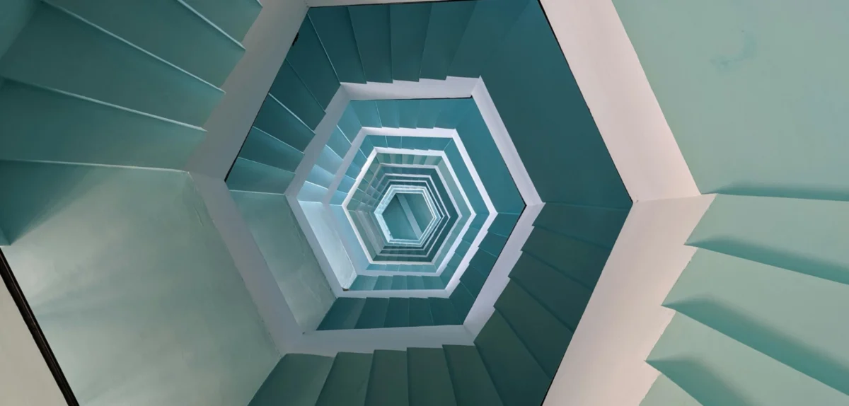 A spiral staircase featuring white steps against a backdrop of blue walls.