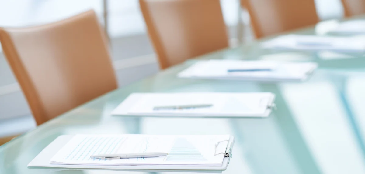 A conference table featuring a pen and a sheet of paper placed on its surface.