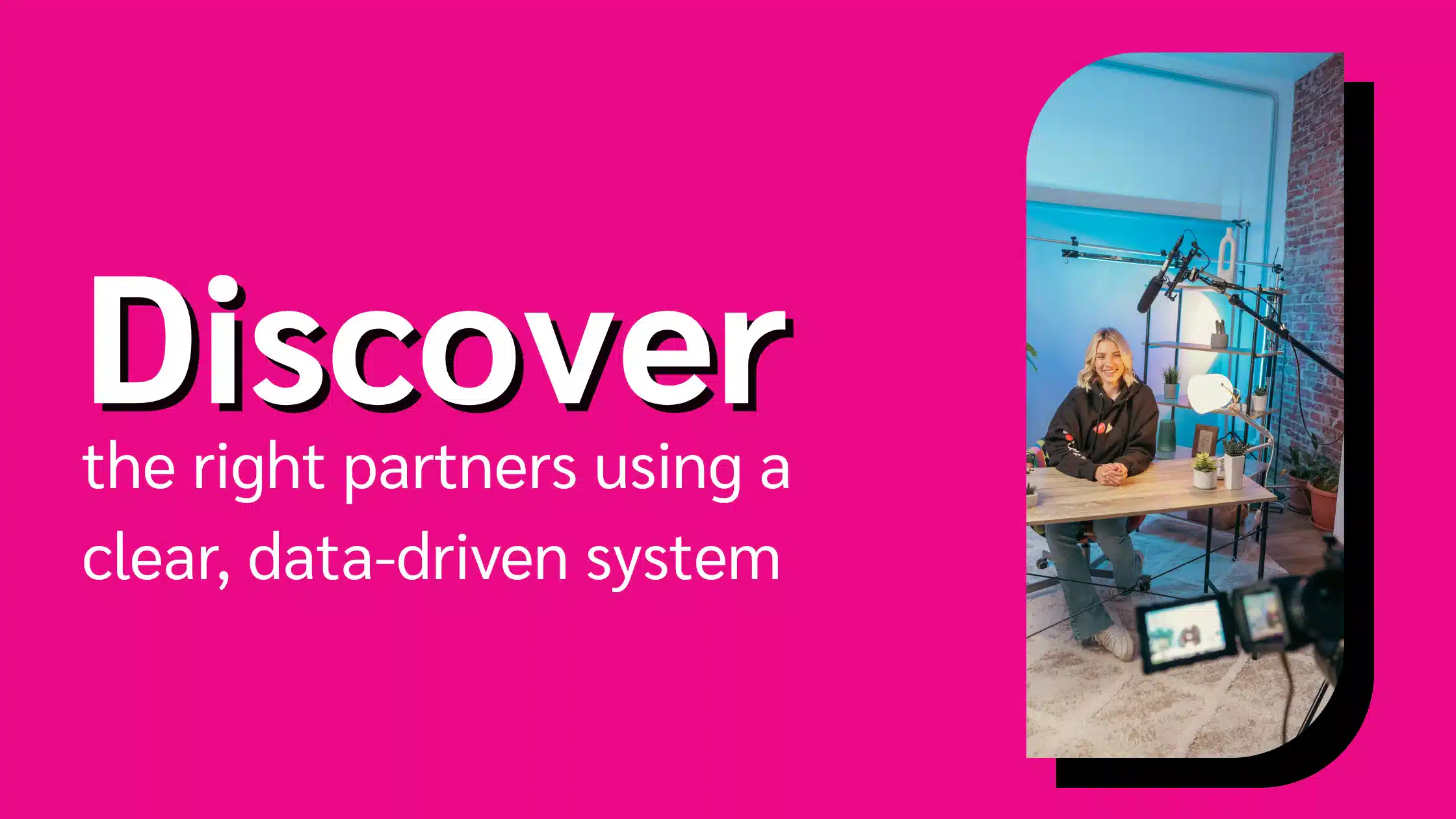 A person sits at a desk in a brightly lit studio, surrounded by plants and cameras, promoting partnership discovery using data-driven methods.