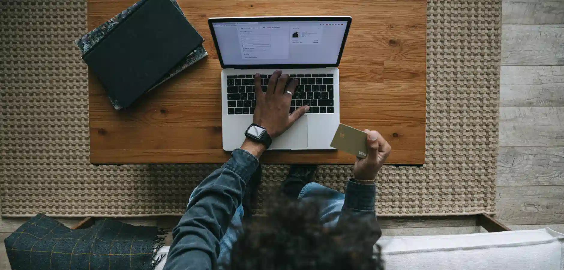 A woman working on a laptop while seated at a wooden table, focused on her task.