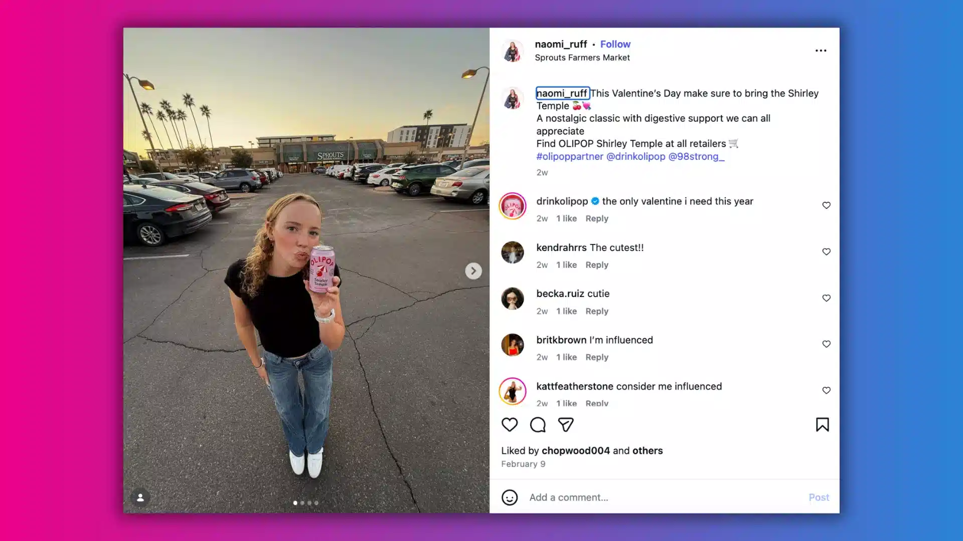 A person holds a pink drink while standing in a parking lot at sunset, with palm trees and stores in the background.