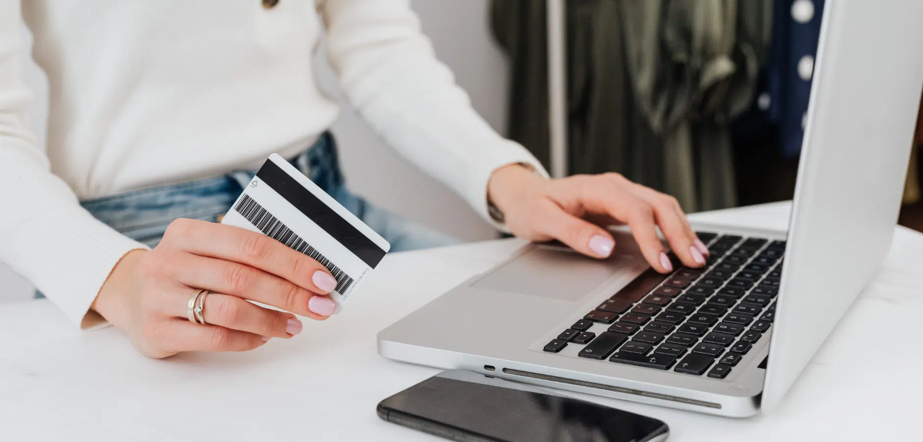 A woman using a laptop while holding a credit card, focused on online shopping or banking activities.