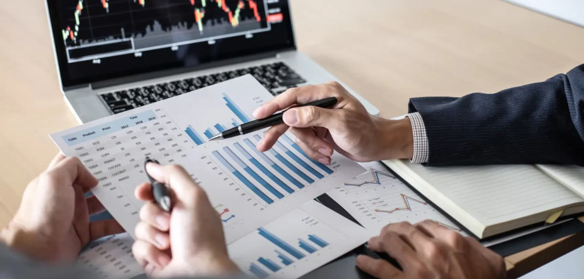 Business professionals analyzing graphs and documents during a collaborative meeting in a modern office setting.